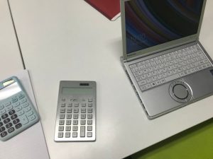パソコンと電卓が机の上に広げられている様子